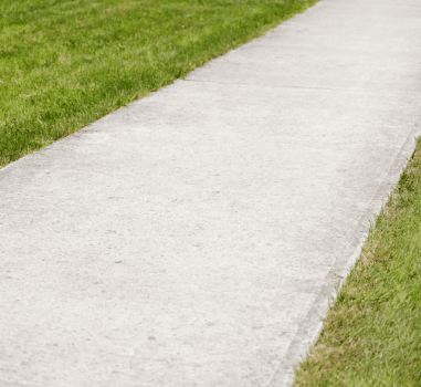 A photo of a sidewalk surrounded by grass